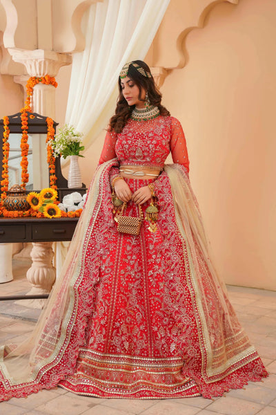 Woman in a red and gold traditional outfit standing in a decorated indoor setting.